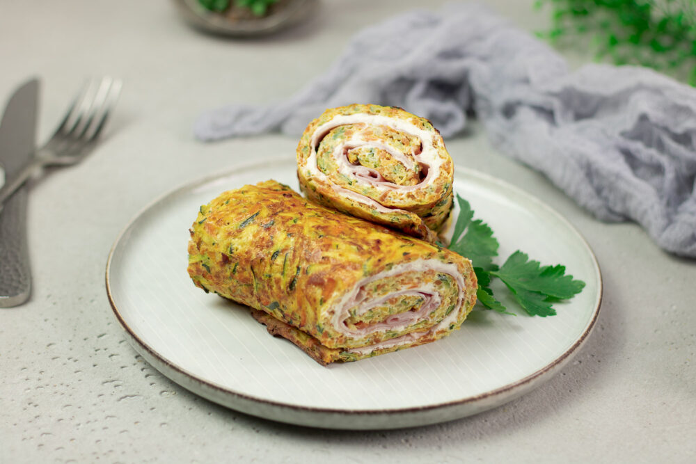 Diese Gemüserolle mit Schinken und Kräuterquark ist perfekt zum Mitnehmen. Man kann sie optimal kalt essen. Der Teig besteht aus Ei, Zucchini, Frischkäse und Karotte.